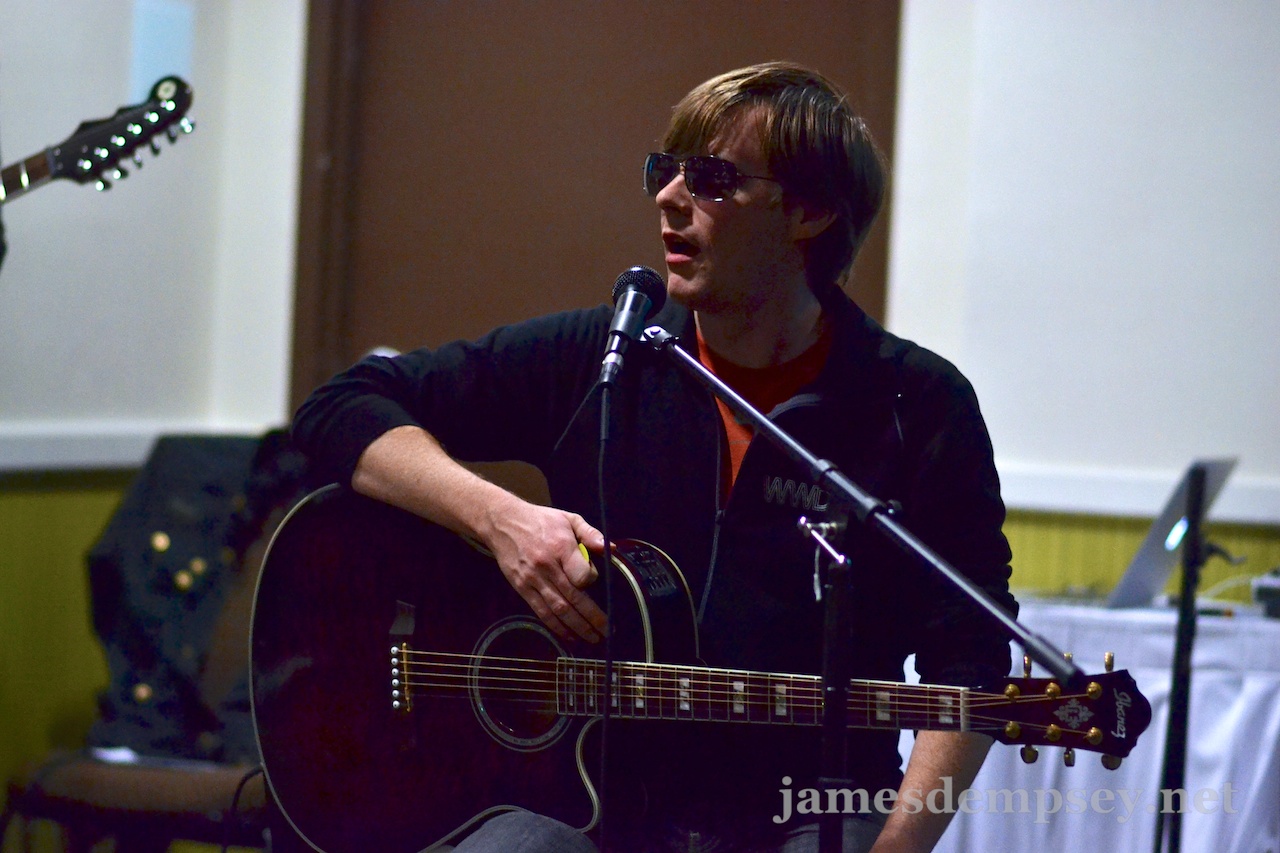 Jonathan Penn sitting with guitar, sunglasses on