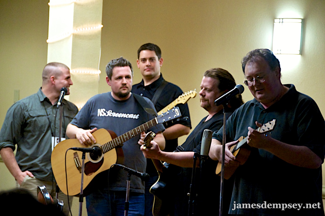 Nathan Sjoquist, Ben Scheirman, Nathan Eror, Daniel Pasco and James Dempsey at microphones, with instruments, performing