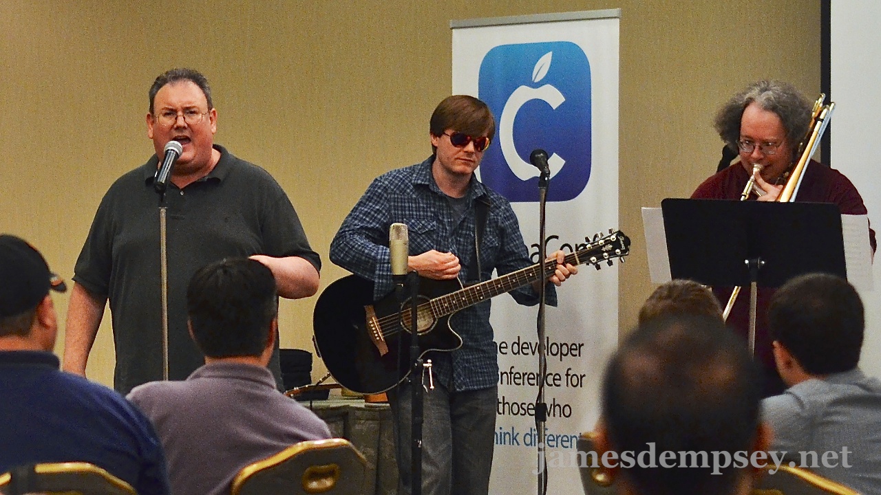 James Dempsey at the microphone, Jonathan Penn playing guitar and Mark Dalrymple playing trombone at CocoaConf DC