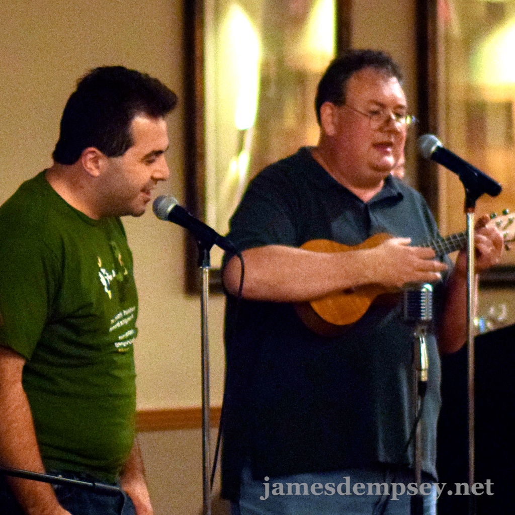 Matt Smollinger singing at microphone with James Dempsey playing ukulele and singing into microphone